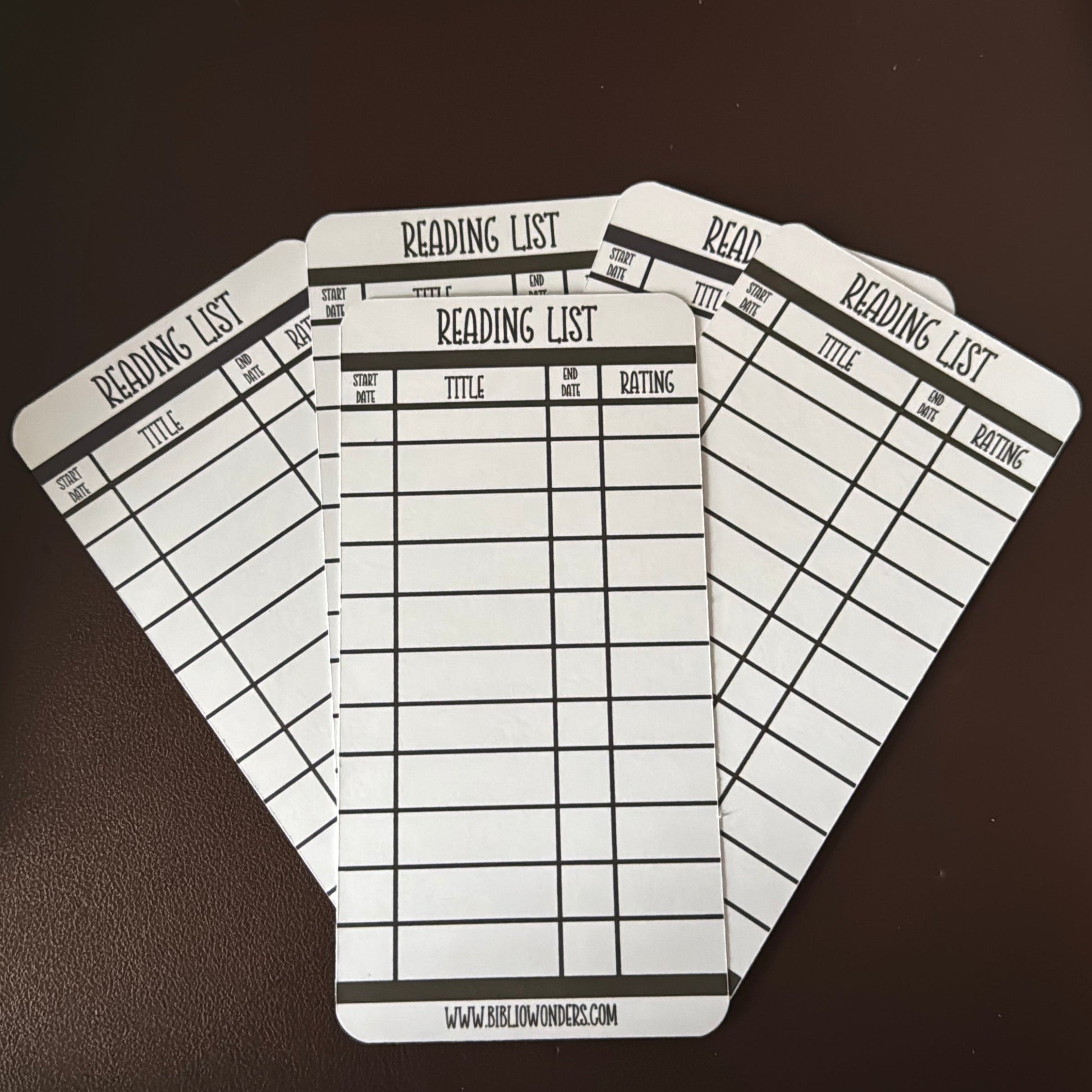 Four identical reading list bookmarks on a dark surface